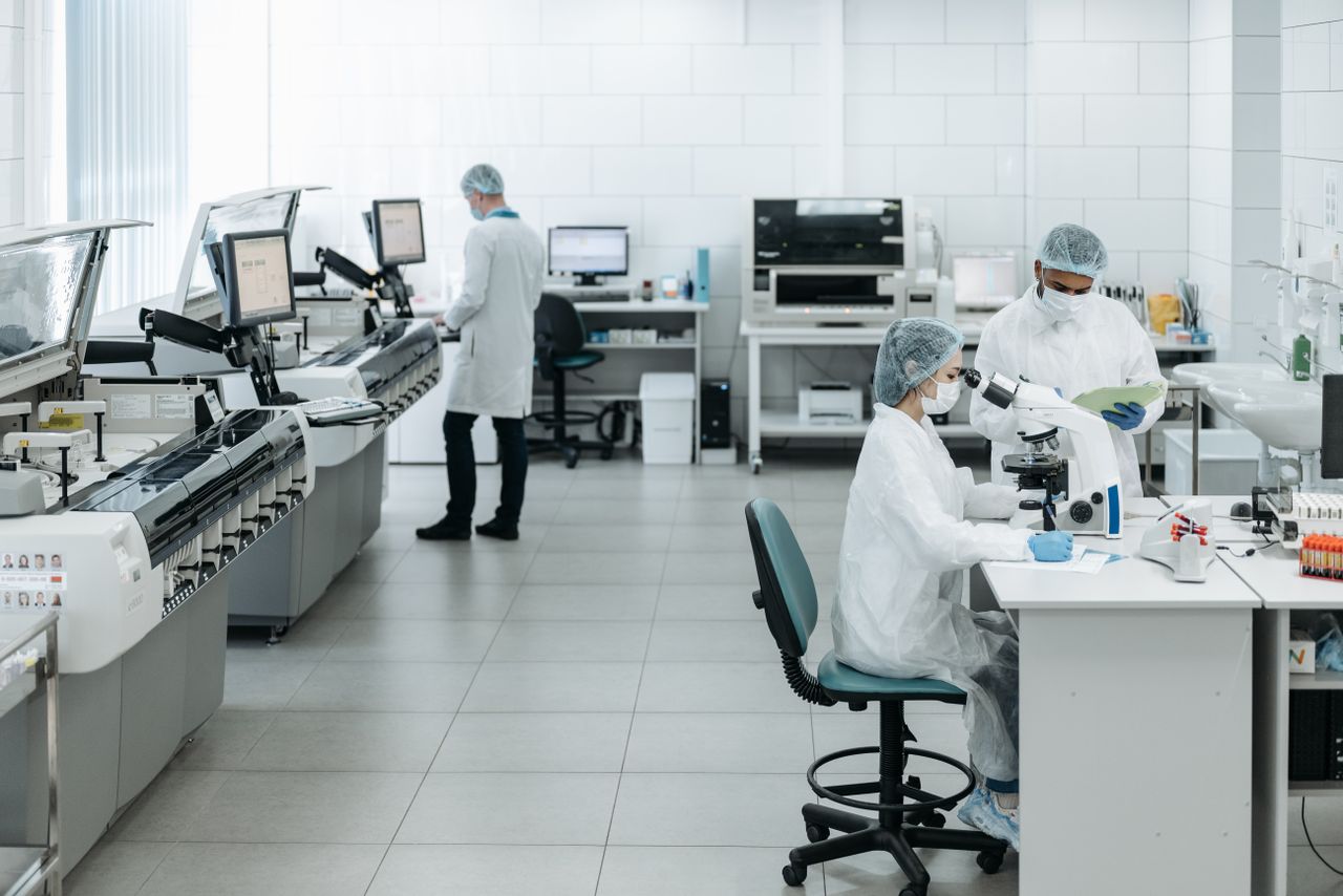 Home Researchers in lab coats performing experiments with advanced equipment in a laboratory.
